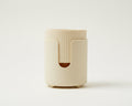 A cream-colored cylindrical plastic container or holder with a ribbed top and a cutout on the front.