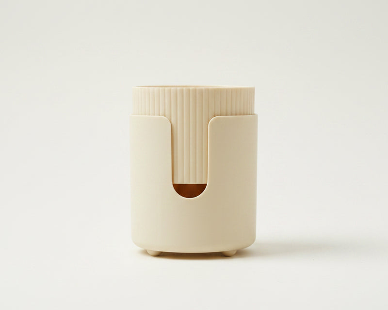 A cream-colored cylindrical plastic container or holder with a ribbed top and a cutout on the front.