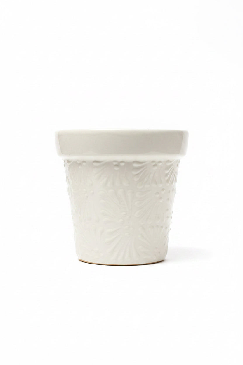 A white ceramic planter pot with embossed floral patterns.