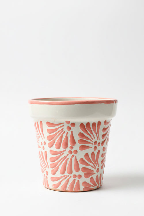 A handmade ceramic planter with a white base and terracotta red textured floral patterns.