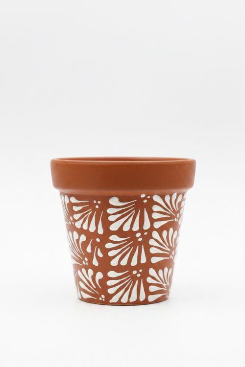 A terracotta-colored ceramic planter pot with a white hand-painted fan pattern.