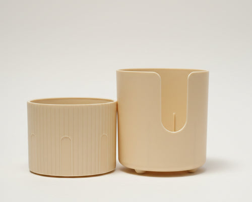 Two cream-colored plastic cylindrical containers or holders with a ribbed texture and a U-shaped cutout.