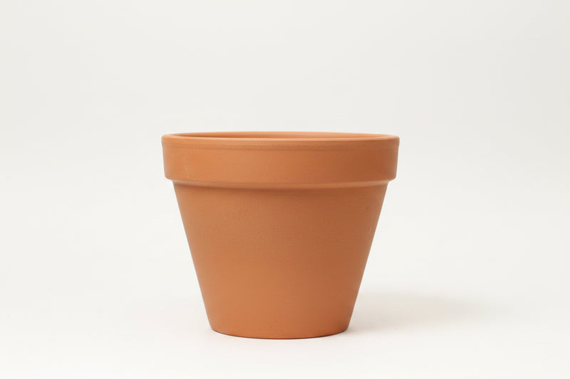 A terracotta clay flower pot with a white barcode sticker on the rim.