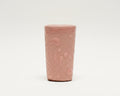 A small pink ceramic cup with a textured, hand-painted abstract pattern.