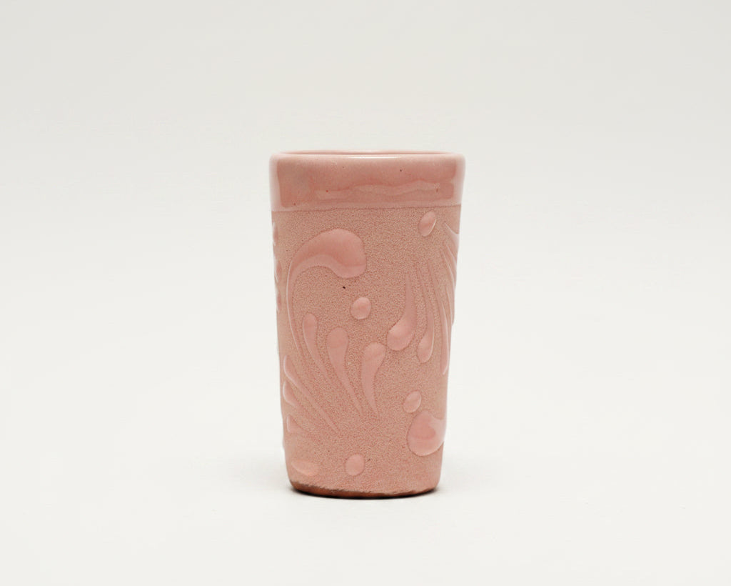 A small pink ceramic cup with a textured, hand-painted abstract pattern.